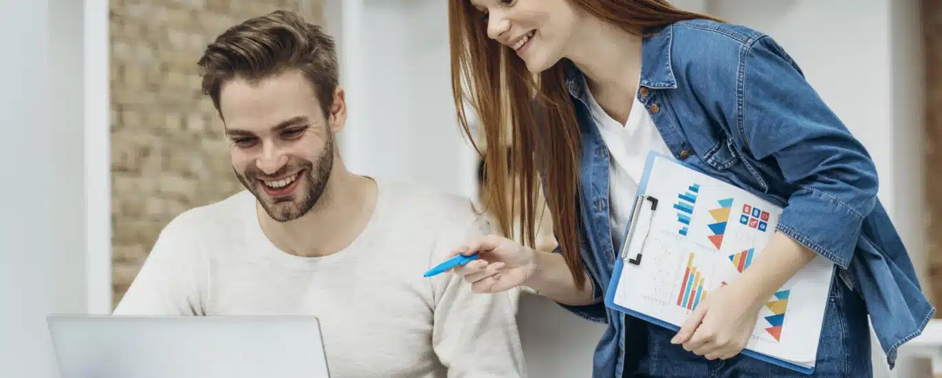 Une collègue de Plyvexia Agency discute avec son collègue dans un bureau moderne, illustrant la communication et l’esprit d’équipe