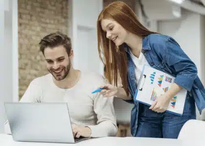 Une collègue de Plyvexia Agency discute avec son collègue dans un bureau moderne, illustrant la communication et l’esprit d’équipe